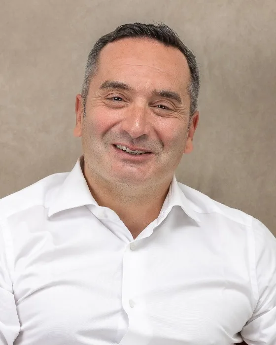 Imprenditore sorridente in camicia bianca su fondo beige, ritratto di Ilia Da Lozzo